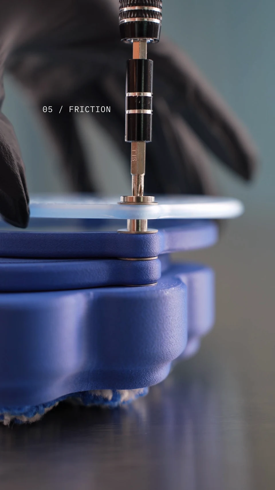 A screwdriver fitting the central pivot through the stacked rotating layers.