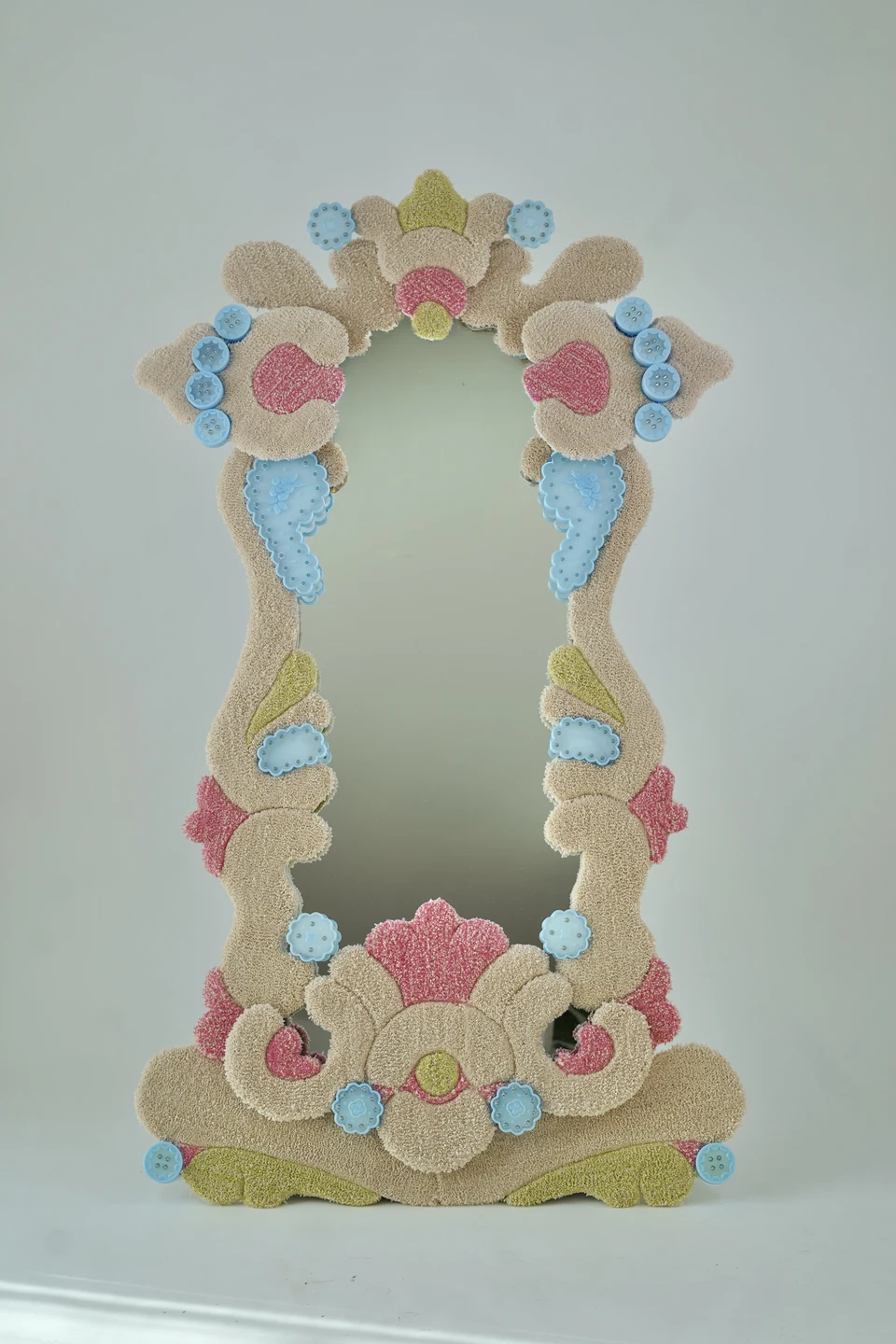 The full-length Receiver mirror framed by cream, pink and yellow tufted forms and translucent blue printed details.