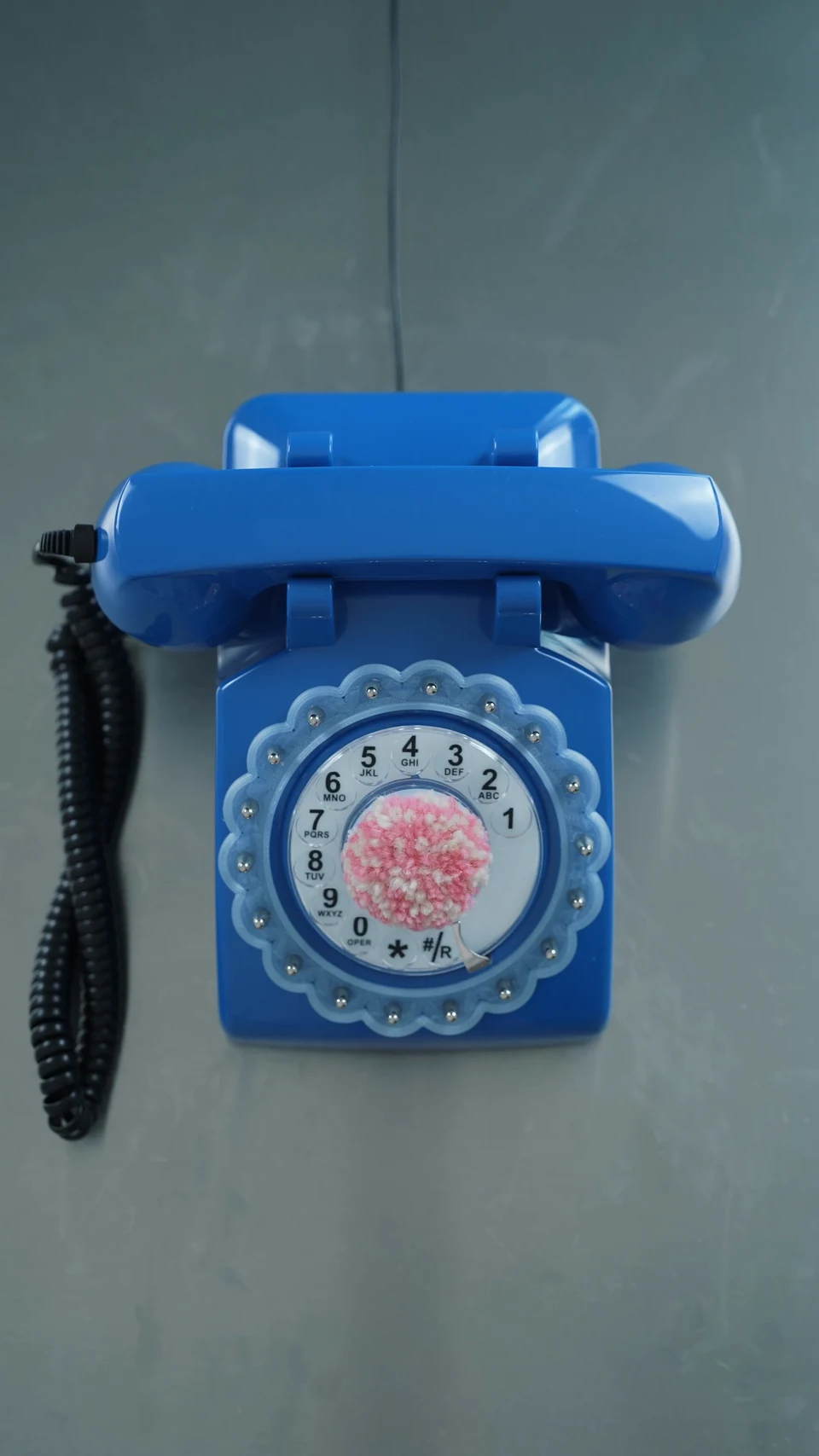 The modified blue telephone with a scalloped dial surround and a tufted pink centre.